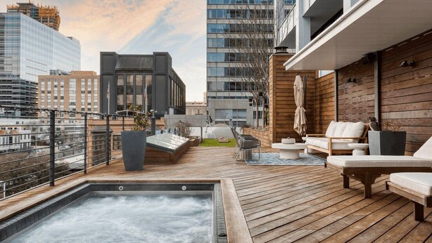 A rooftop terrace with a hot tub, outdoor seating, and a view of the cityscape.