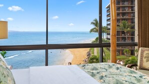Una habitación con un ventanal grande que da a una playa y un edificio de rascacielos.