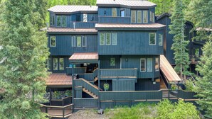 A multi-level wooden cabin with multiple decks and staircases, surrounded by dense forest. - Manitou Riverhouse 115 by Avantstay Spacious Condo in the Centre of Telluride (Telluride)