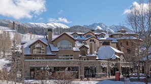 A large, multi-story building with a stone facade, multiple windows, and a snow-covered roof.