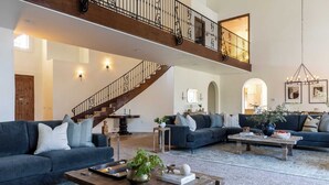 Ein geräumiges Wohnzimmer mit hoher Decke, einer Treppe und einem Balkon.