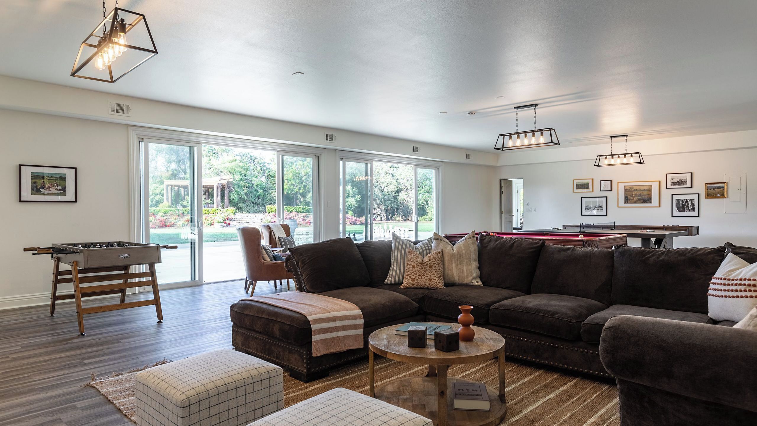 A spacious living room with a sectional sofa, a pool table, and a foosball table.