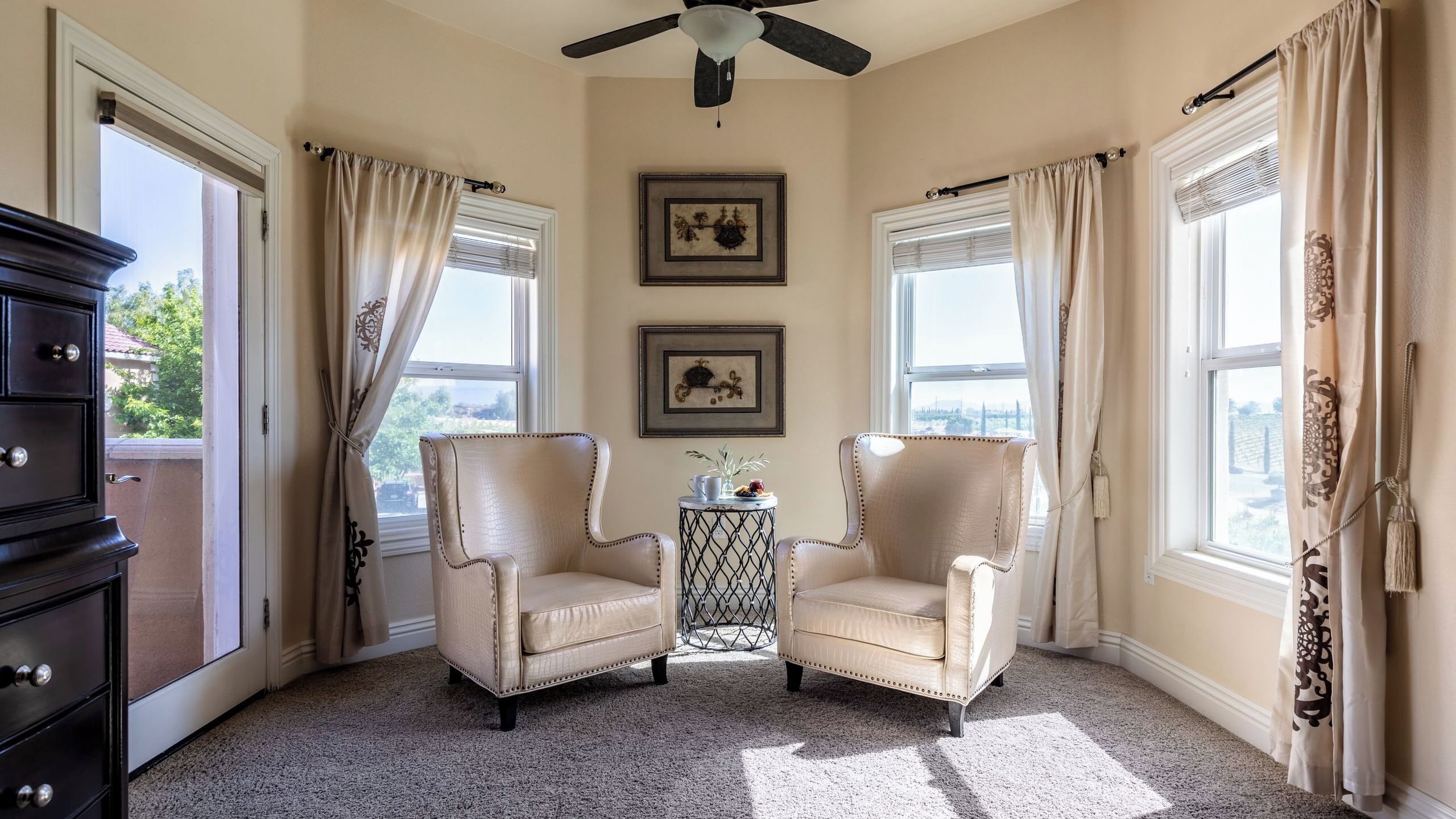 A room with two leather armchairs, a small table with a vase, and two framed pictures on the wall.