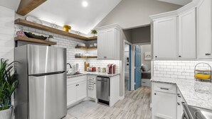 Una cocina moderna con armarios blancos, un refrigerador de acero inoxidable y una viga de techo de madera.