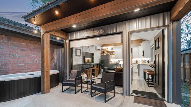 Un espacio exterior moderno con un letrero que dice 'WELCOME', un jacuzzi y un patio con asientos.