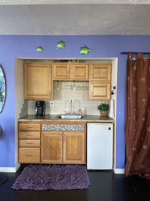 A compact kitchen with wooden cabinets, a built-in dishwasher, and a coffee maker.