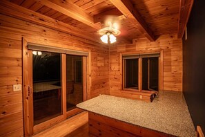 Interior de una cabaña de madera con zona de cocina, que incluye una encimera de granito y un ventilador de techo.