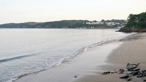 Une plage avec une mer calme, un rivage sablonneux et des bâtiments en arrière-plan.