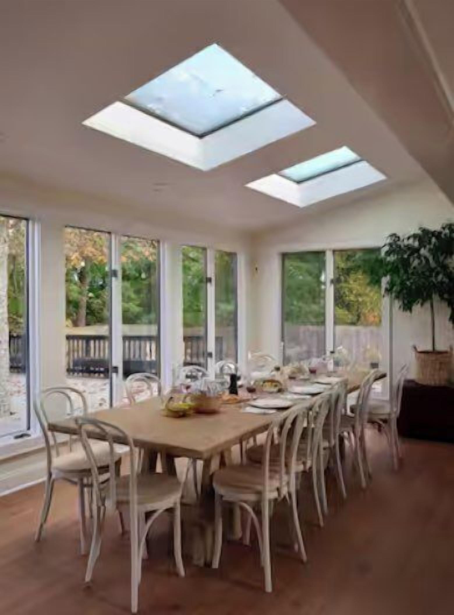 Un espace repas avec une longue table, des chaises et des fenêtres de toit.
