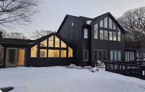 Et moderne hus med et stort vindue, en terrasse og en snedækket have.