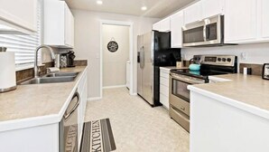 A modern kitchen with white cabinets, stainless steel appliances, and a tiled backsplash. - 2Min>RedhawkGolfCourse★LongStays★300mbps★1300ft²★ (Nampa)