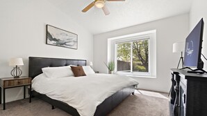 A bedroom with a bed, a nightstand, a desk, a ceiling fan, a window, and a TV. - *Backyard*King*Parking*100Mbps*Smart TV*Bbq*W/D (Boise)