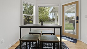A dining area with a table and four benches, large windows, and a door leading outside. - *Backyard*King*Parking*100Mbps*Smart TV*Bbq*W/D (Boise)