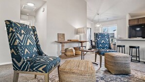 Een moderne woonkamer met twee gestreepte fauteuils, een ronde salontafel en een geweven poef.