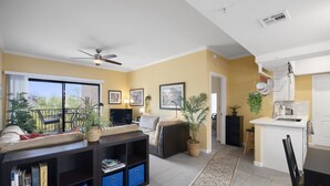 A living room with a sofa, TV, and a balcony with plants. - Cozy Desert Getaway*Inviting Pool*Smart TV*Gym (Fountain Hills)