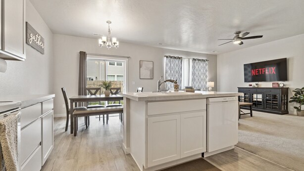 A modern kitchen with white cabinetry, a dining area with a bench, and a living room with a TV and ceiling fan. - *FirePit*King*Parking*1600ft²*Smart TV*W/D (Meridian)