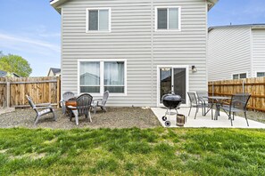 A two-story house with a patio area featuring a grill, chairs, and a table. - *FirePit*King*Parking*1600ft²*Smart TV*W/D (Meridian)