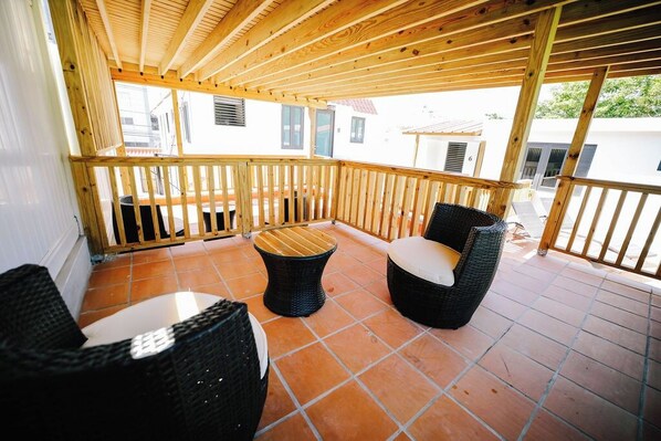 A covered outdoor seating area with wicker furniture and a tiled floor. - Colonial Apartment, Generator, Walk to San Juan (San Juan)