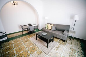 A living room with a sofa, coffee table, chairs, and a patterned floor.