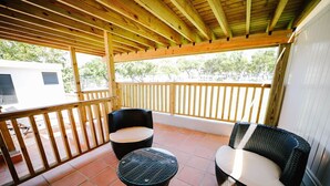 A covered patio area with two wicker chairs and a small round table, wooden railings, and a view of a white building and trees. - Original Spanish Architecture in the Heart of SanJuan w/Parking (San Juan)