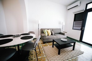 Un salon moderne avec un canapé gris, une table de salle à manger ronde et une table basse noire.