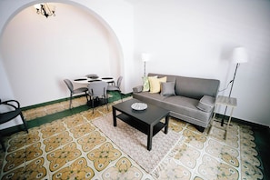 A living room with a sofa, coffee table, chairs, and a patterned floor.