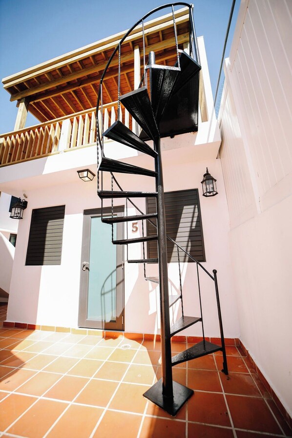 A spiral staircase with a metal railing, leading to a wooden deck.