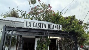 Une devanture de magasin avec une enseigne indiquant « LA CASITA BLANCA » et une statue de vache décorative placée à l’extérieur.
