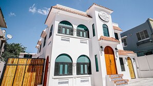 A two-story building with a white facade, a wooden door, and a sign that reads "CASA SAGRADO". - Original Spanish Architecture in the Heart of SanJuan w/Parking (San Juan)