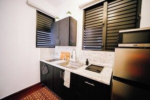 A kitchen with a sink, countertop, cabinets, and a refrigerator.