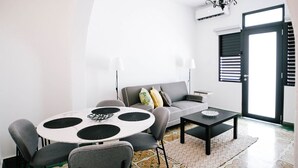 A modern living room with a round table, grey sofa, and patterned floor tiles. - Original Spanish Architecture in the Heart of SanJuan w/Parking (San Juan)