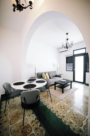 Un salon moderne avec une table ronde, un canapé gris et des carreaux de sol à motifs.
