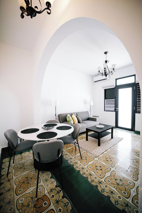 A modern living room with a round table, grey sofa, and patterned floor tiles.