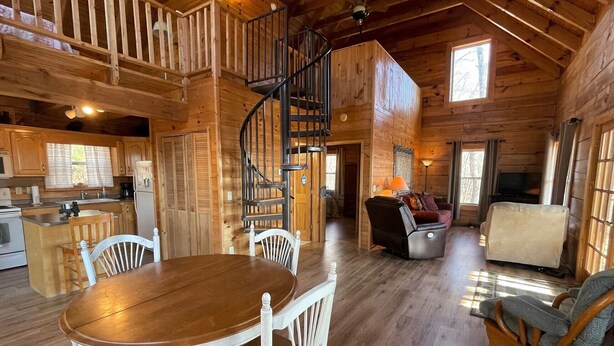 Interior de una cabaña de madera con comedor, cocina y sala de estar.
