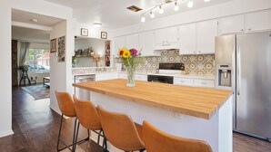 A modern kitchen with white cabinets, a wooden island with bar stools, and a stainless steel refrigerator. - Cozy and modern townhome in Aurora, 5min from highway ! (Aurora)