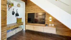 A modern interior with a wooden sloped ceiling, a mounted TV, and a bench with storage baskets. - Cozy and modern townhome in Aurora, 5min from highway ! (Aurora)