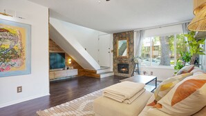 A modern living room with a sofa, a fireplace, a staircase, and a large window with a view of the outside. - Cozy and modern townhome in Aurora, 5min from highway ! (Aurora)
