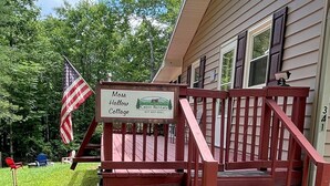 Eine Holzhütte mit Veranda, ein Schild für Moss Hollow Cabin Rentals, eine amerikanische Flagge und ein Steinweg, der zum Eingang führt.