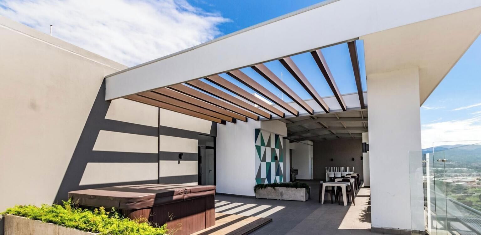 Une terrasse extérieure moderne, dotée d’une pergola en bois, d’un espace salon et offrant une vue sur la ville.
