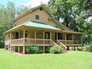 A two-story house with a porch and a green roof.