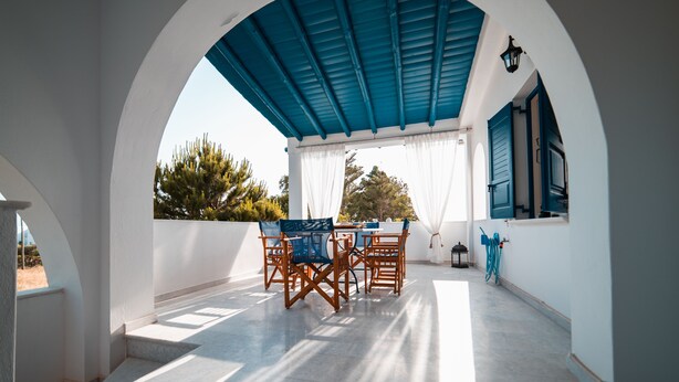 A covered outdoor seating area with a table and chairs, a lantern, and a hose. - Cycladic Seaside House “Konstantinos” by Kastraki Family House (Kastraki Naxos)
