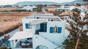 A white building with blue shutters, a balcony, and a view of the surrounding area. - Cycladic Seaside House “Konstantinos” by Kastraki Family House (Kastraki Naxos)