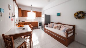 A modern kitchen with wooden cabinets, a dining table, and a sofa. - Cycladic Seaside House “Konstantinos” by Kastraki Family House (Kastraki Naxos)