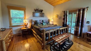 Ein rustikales Schlafzimmer mit einem hölzernen Bett, einer Bank, einem Nachttisch und einem Fenster mit Jalousien.