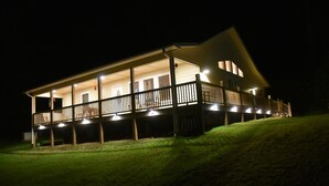 Una casa de dues plantes amb un balcó, il·luminada per llums exteriors.