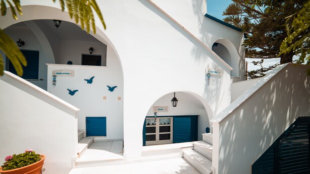 A white building with blue doors and windows, a staircase, and a potted plant. - Cycladic Seaside House “Eleftheria” in Naxos Island by Kastraki Family House (Kastraki)