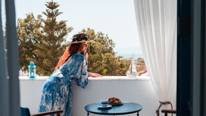 A balcony with a view of trees and a sailboat. There is a table with a cup and a pastry. - Cycladic Seaside House “Eleftheria” in Naxos Island by Kastraki Family House (Kastraki)