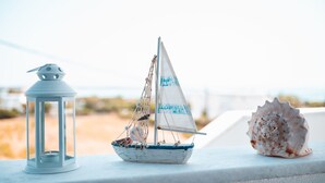 A small sailboat model, a white lantern, and a seashell on a ledge. - Cycladic Seaside House “Eleftheria” in Naxos Island by Kastraki Family House (Kastraki)