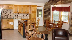 Una cocina con armarios de madera, salpicadero de azulejos y una zona de comedor con sillas y mesa de madera.