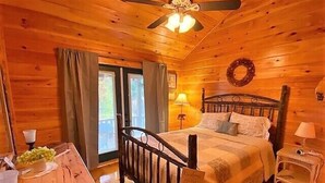 A wooden cabin bedroom with a bed, bedside tables, a desk, and a dining table. - Big Rock Ridge - Easy Access for mountain views! (Murphy)